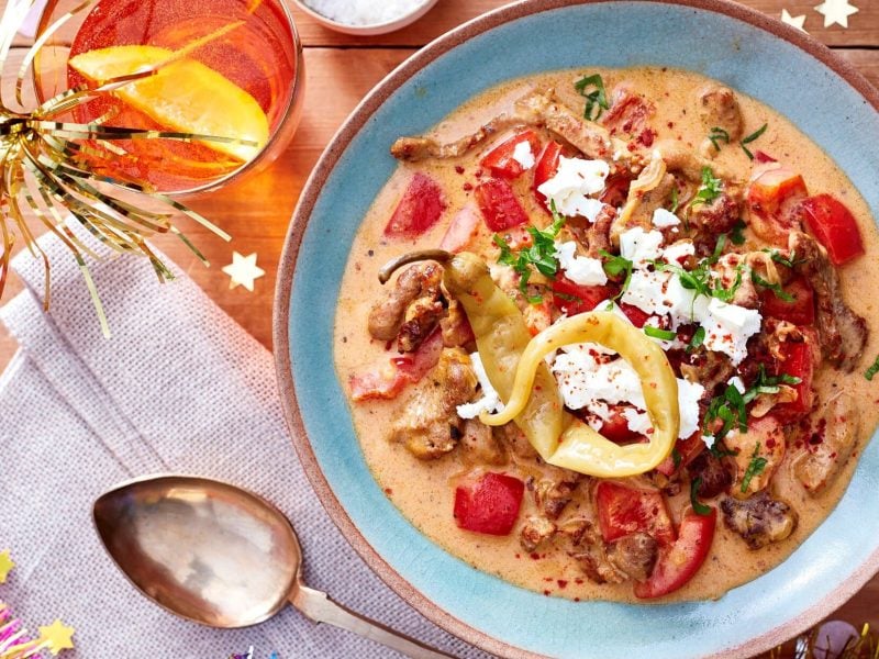 Gyrossuppe mit knackiger Paprika in einer blauen Schale. Daneben Cocktails und Party-Dekoration