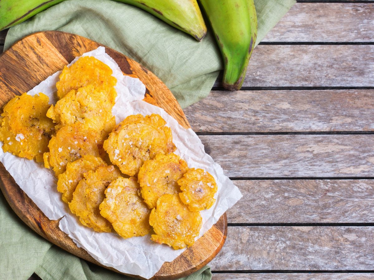 Kochbananen-Chips, frittiert auf einem Brett mit Backpapier, auf einem Holztisch