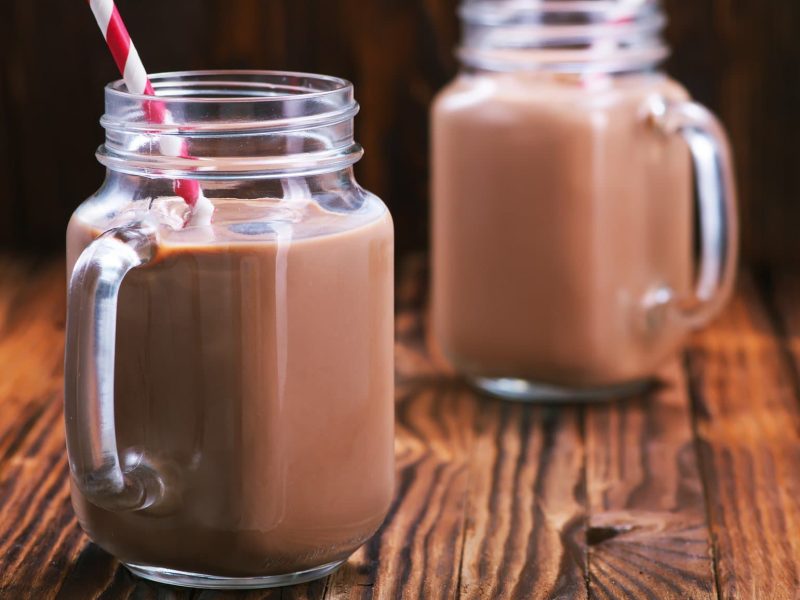Zwei Gläser mit Nutella-Milch stehen auf einem dunklen Untergrund. In jedem Glas steckt ein Strohhalm.