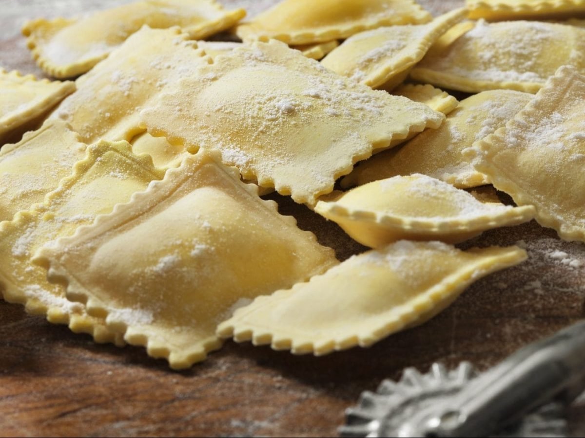 Auf einer Holzplatte lieben gefüllze Nudeln, die nach einem Ravioli-Grundteig-Rezept zubereitet wurden.