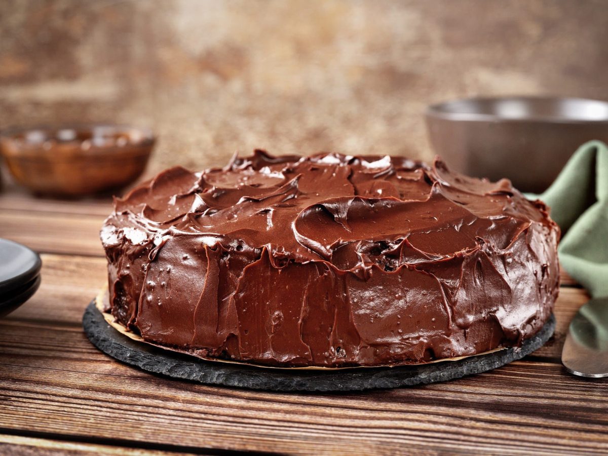 Rote-Bete-Schokokuchen mit cremiger Schokoglasur auf einer Platte auf hölzernem Untergrund