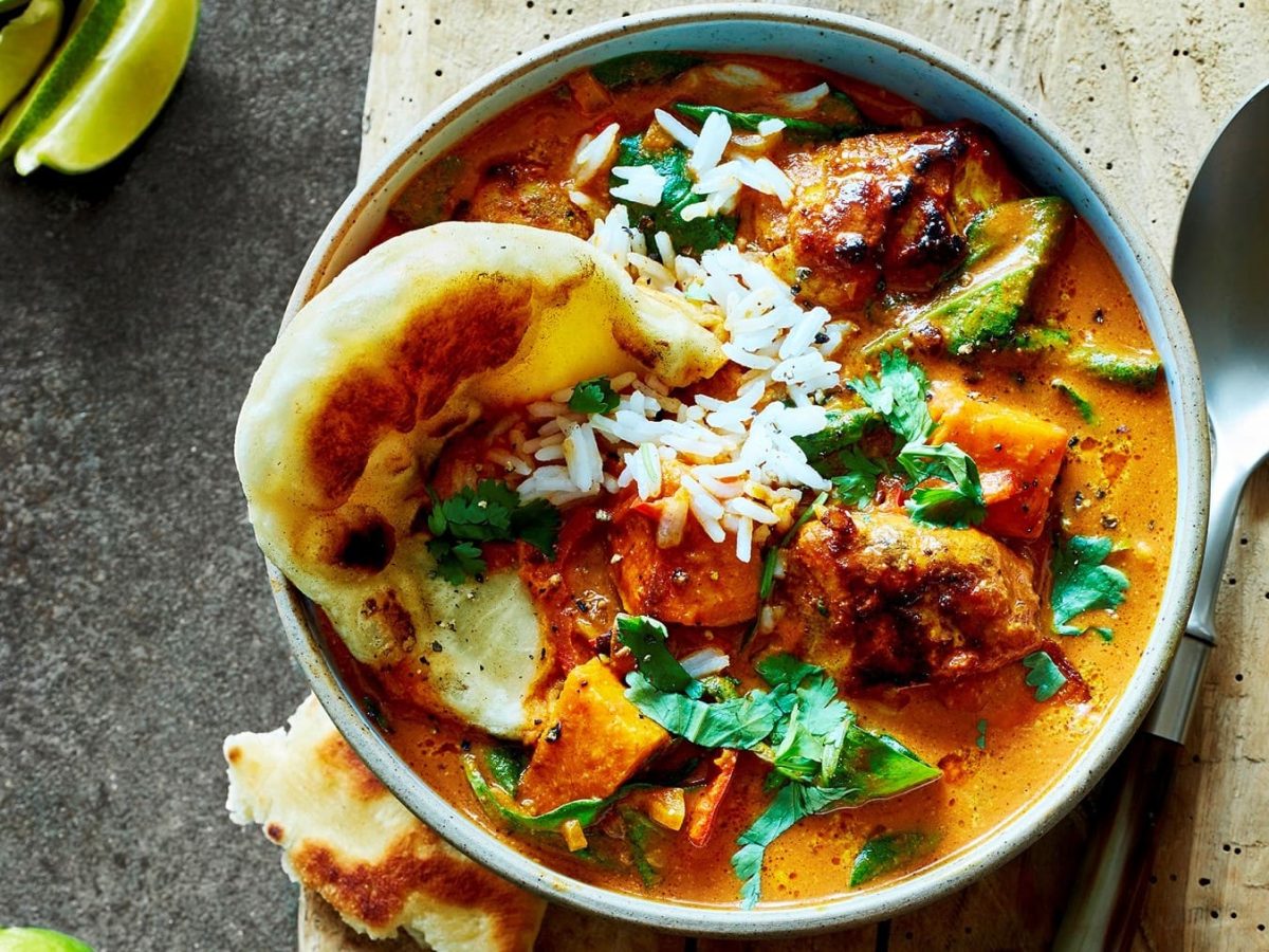 Eine Portion Butter Chicken mit Reis serviert in einer Schüssel.