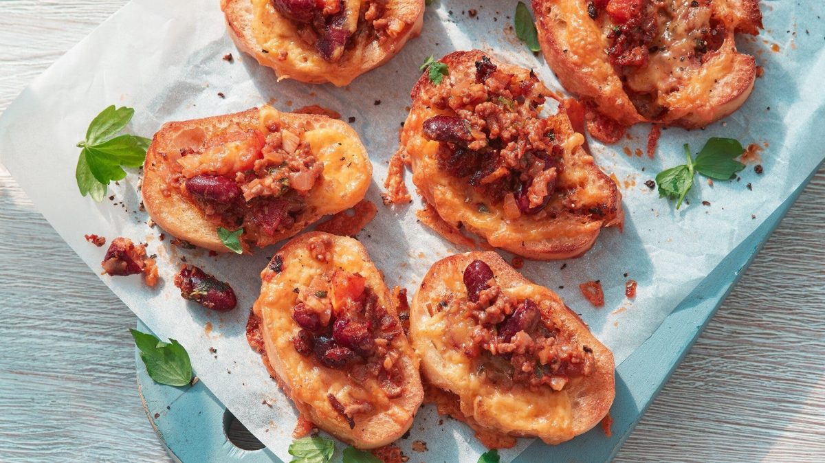 Unser Chili-con-Carne-Baguette liegt ofenfrisch auf Butterbrotpapier auf dem Tisch.