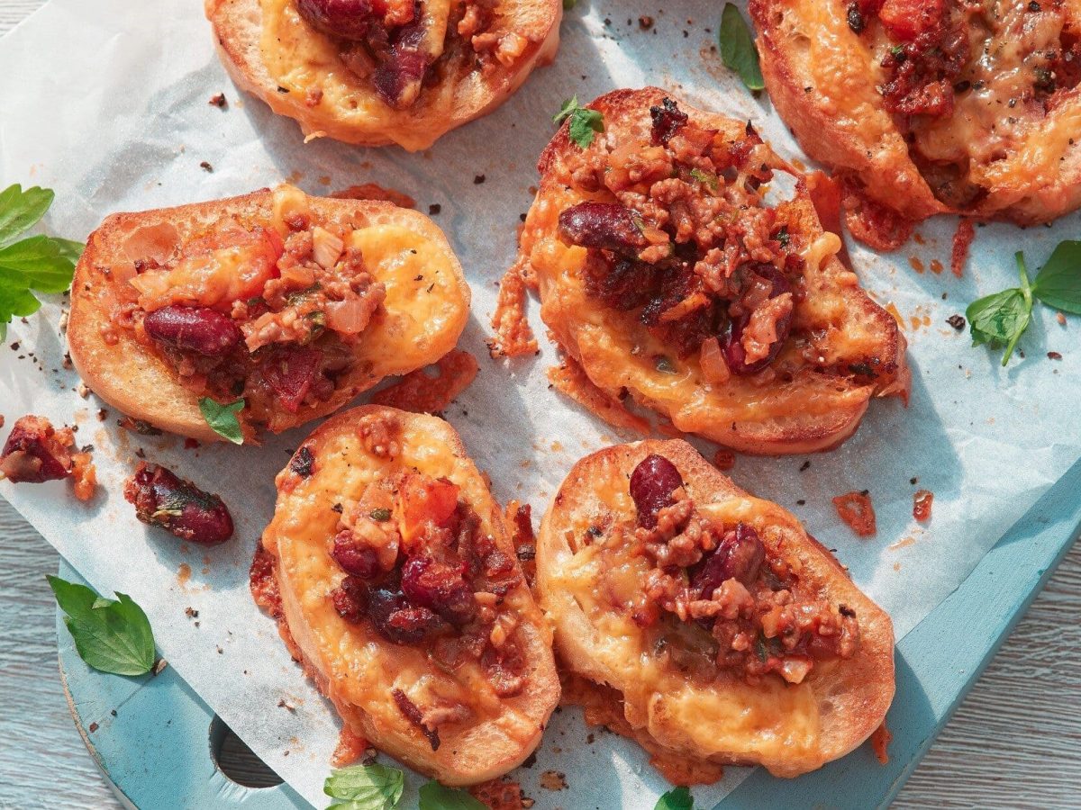 Unser Chili-con-Carne-Baguette liegt ofenfrisch auf Butterbrotpapier auf dem Tisch.