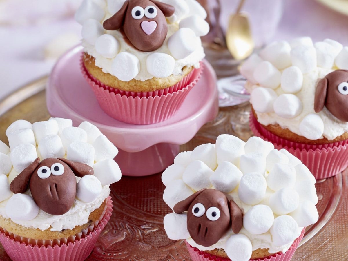 Auf einem Tablett stehen vier Schäffchen Muffins. Sie sind mit Marshmallows und Fondant dekoriert.