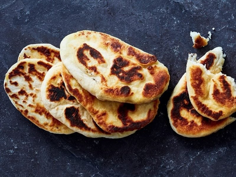 Mehrere Scheiben Naan auf dunklem Steinuntergrund