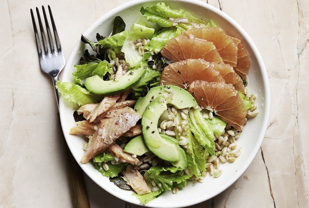 Saftiger Forellen-Salat mit Grapefruit, Avocado, Graupen, Blattsalat und frischem Zitronendressing in einer weißen Schale auf hellem Holztisch, von oben fotografiert.