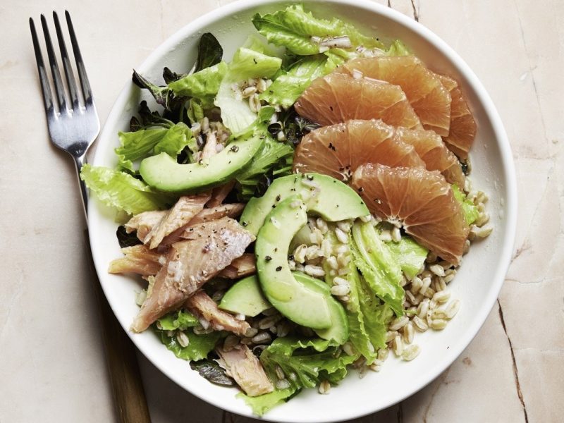 Saftiger Forellen-Salat mit Grapefruit, Avocado, Graupen, Blattsalat und frischem Zitronendressing in einer weißen Schale auf hellem Holztisch, von oben fotografiert.