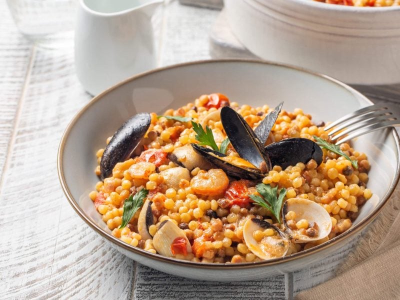 Schale Fregola mit Meeresfrüchten auf weißem Tisch