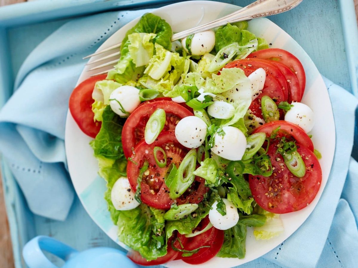 Unser grüner Salat mit Caprese fein angerichtet in einer Salatschüssel.