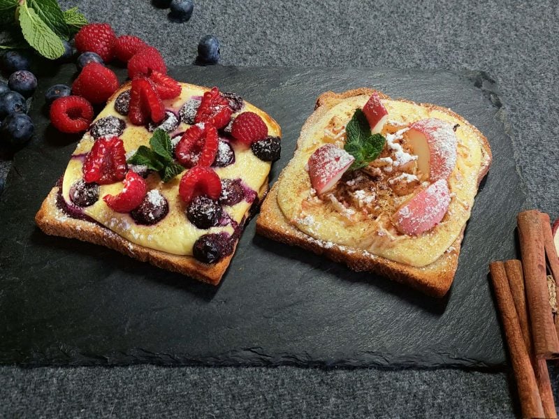 Toasts von oben mit Früchten auf schwarzer Schieferplatte