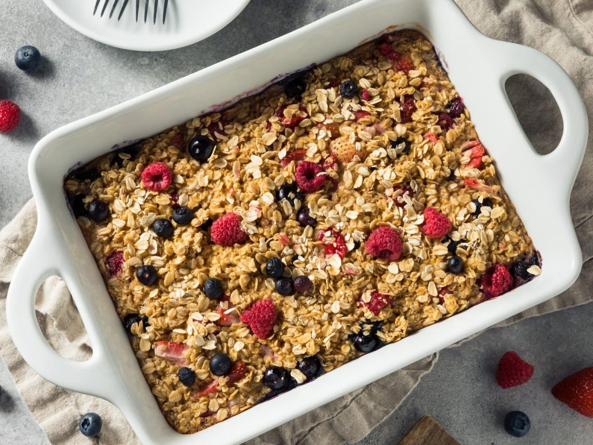 Ein Haferflocken-Auflauf auf einem weißem Tisch mit Beeren.