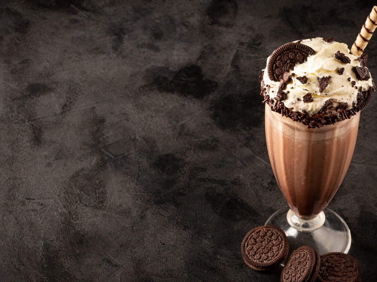 Oreo Milkshake in einem Glas. Das Ganze auf einem dunklen Untergrund.