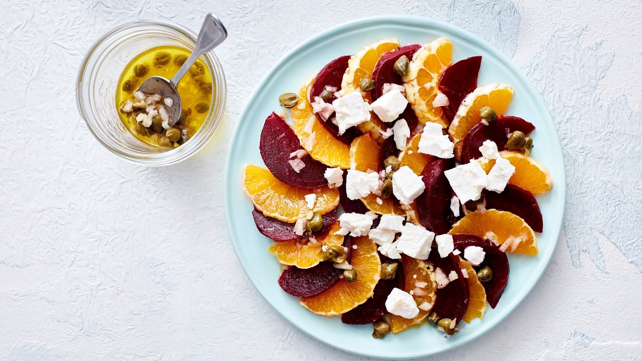 Unser Rote-Bete-Salat mit Orange fein angerichtet auf einem flachen Teller. Dazu ein Kapern-Schalotten-Dressing.