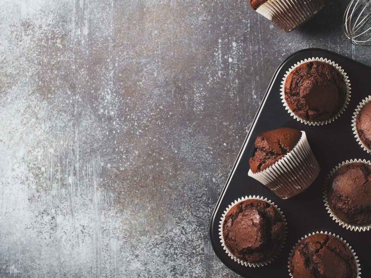 Sechs Schoko-Rotwein-Muffins in einem Muffinblech in der Draufsicht.