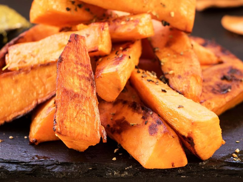 Süße Sweet Potato Wedges auf einer schwarzen Schieferplatte.