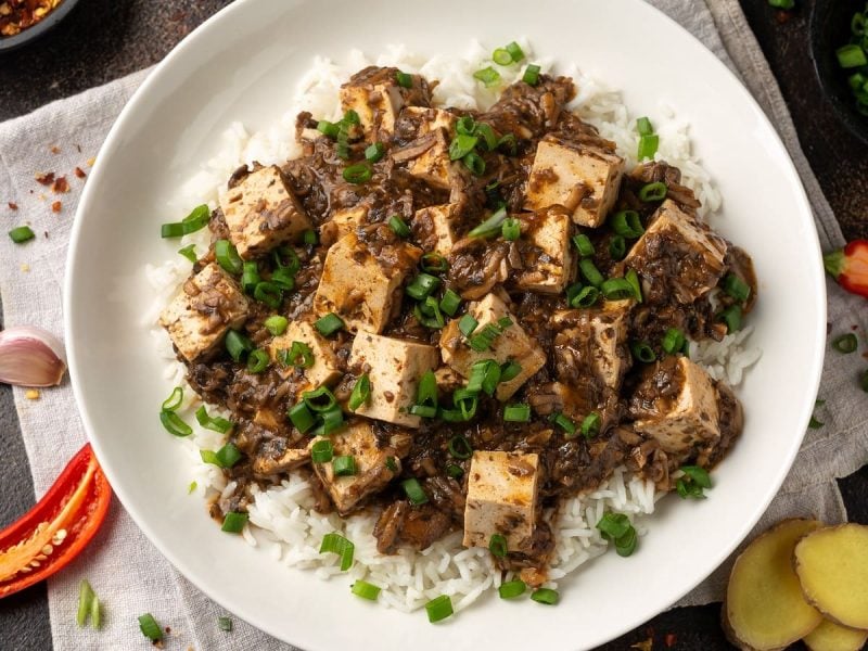 Ein Teller mit veganem Mapo-Tofu neben frischer Chili und Ingwer