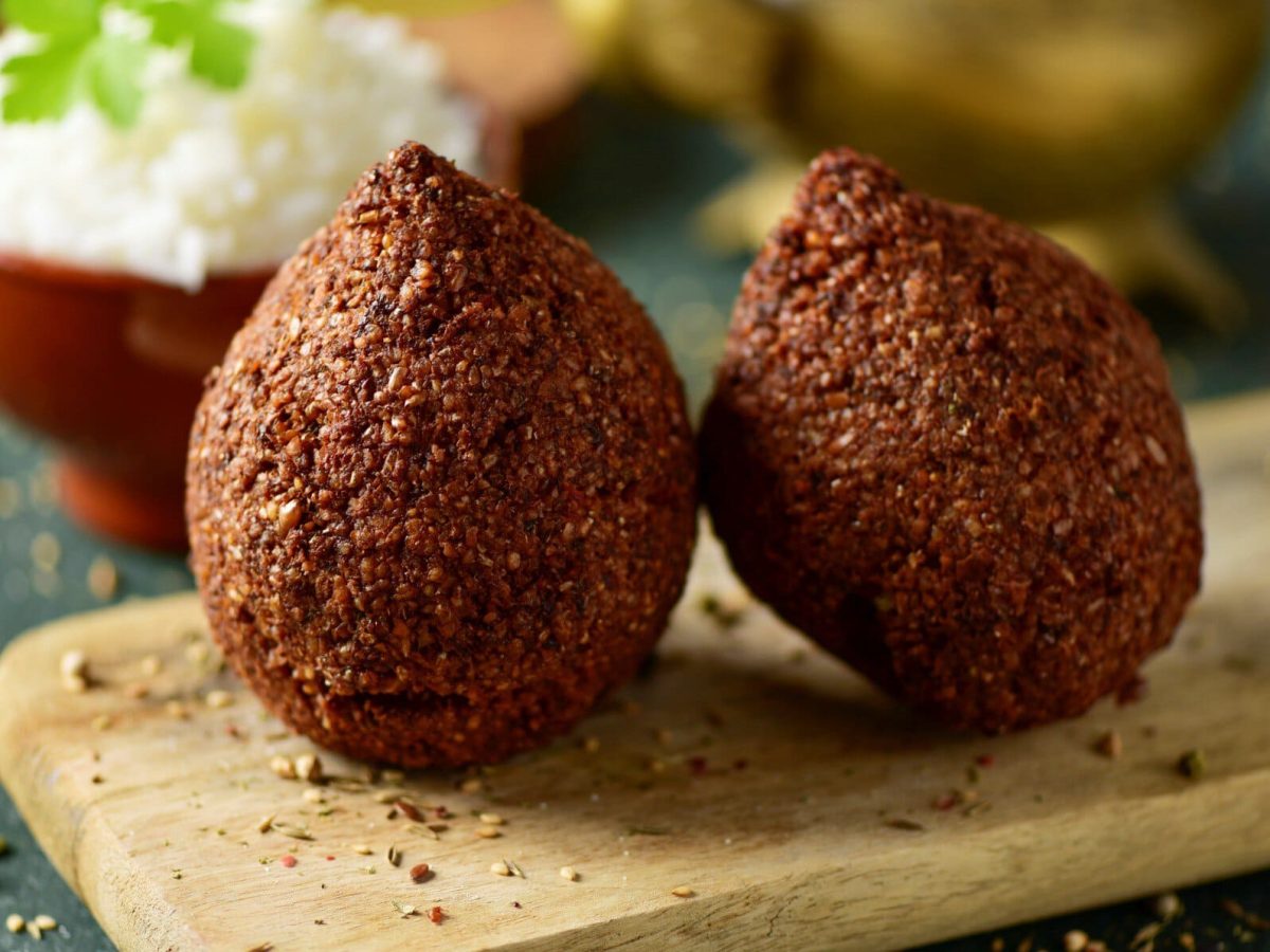 Zwei vegane Kibbeh auf einem Holzbrett.