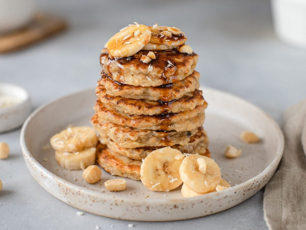 ein Stapel vegane Pancakes mit Haferflocken und Bananenscheiben.