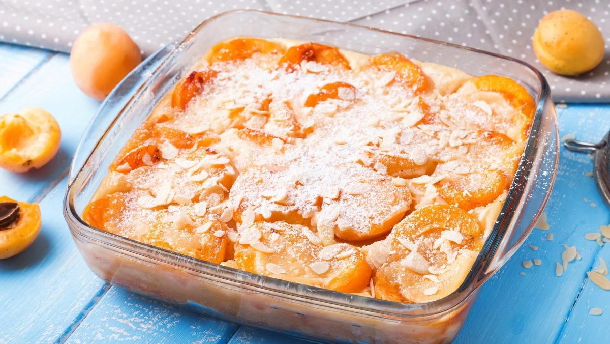 Saftiger Aprikosen-Clafoutis aus Pfannkuchen-Teig und fruchtigen Aprikosen, bestreut mit Mandlen und Puderzucker.