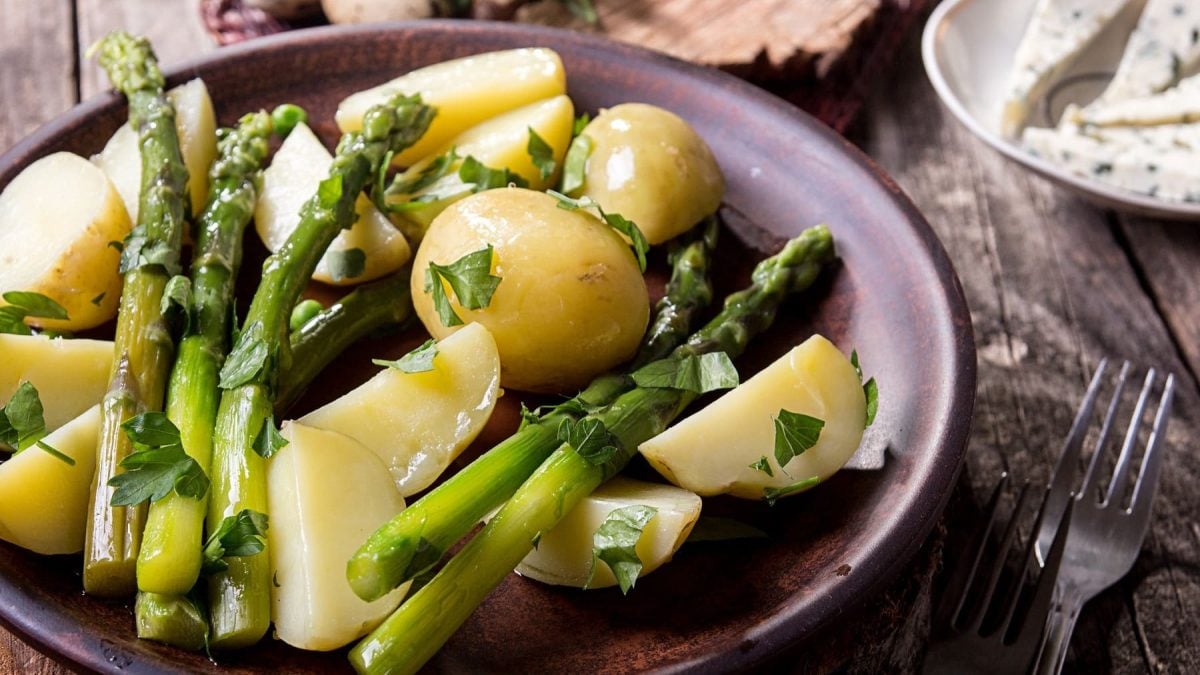 Grüner Spargel mit Kartoffeln auf Teller serviert.