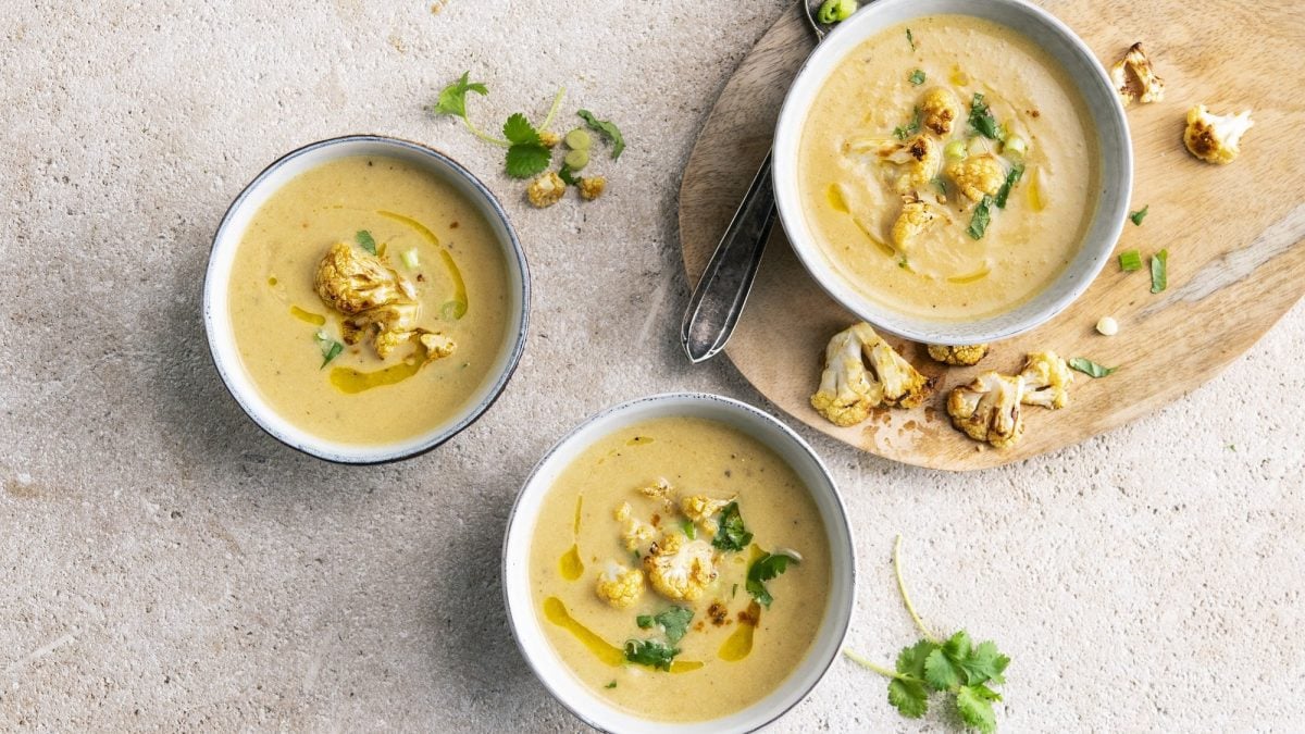 In drei Schüssel ist eine marokkanische Blumenkohlsuppe angerichtet. Sie ist cremig und mit Sellerie garniert.