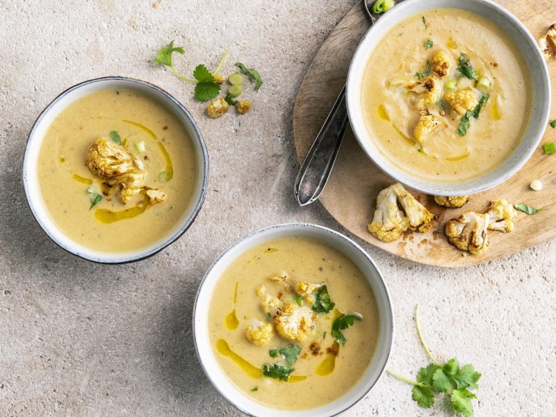 In drei Schüssel ist eine marokkanische Blumenkohlsuppe angerichtet. Sie ist cremig und mit Sellerie garniert.