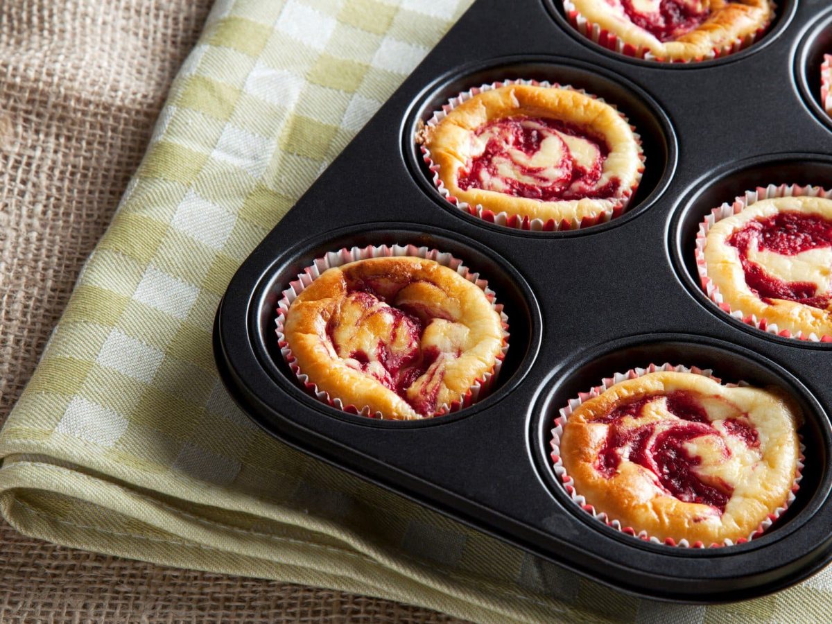 Eine Muffin-Backform gefüllt mit Himbeer-Cheesecake-Muffins.