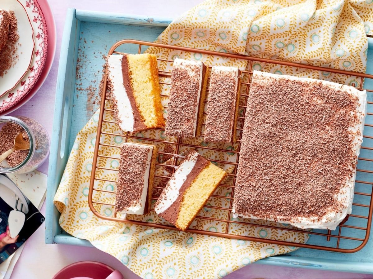 Süße Schoko-Schnitten mit Pudding und Schmand auf einem blauen Tablett, das auf einem gedeckten Tisch steht