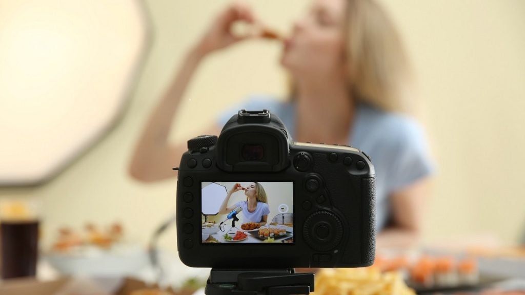 Blonde Frau beim ASMR Eating isst ein Stück Pizza und filmt sich dabei