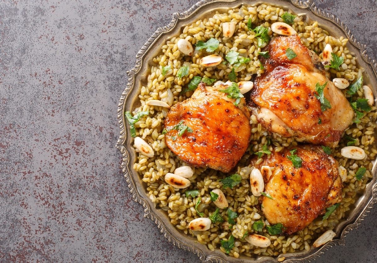 Libanesisches Freekeh mit Hähnchen auf einem Teller auf grauem Stein-Untergrund