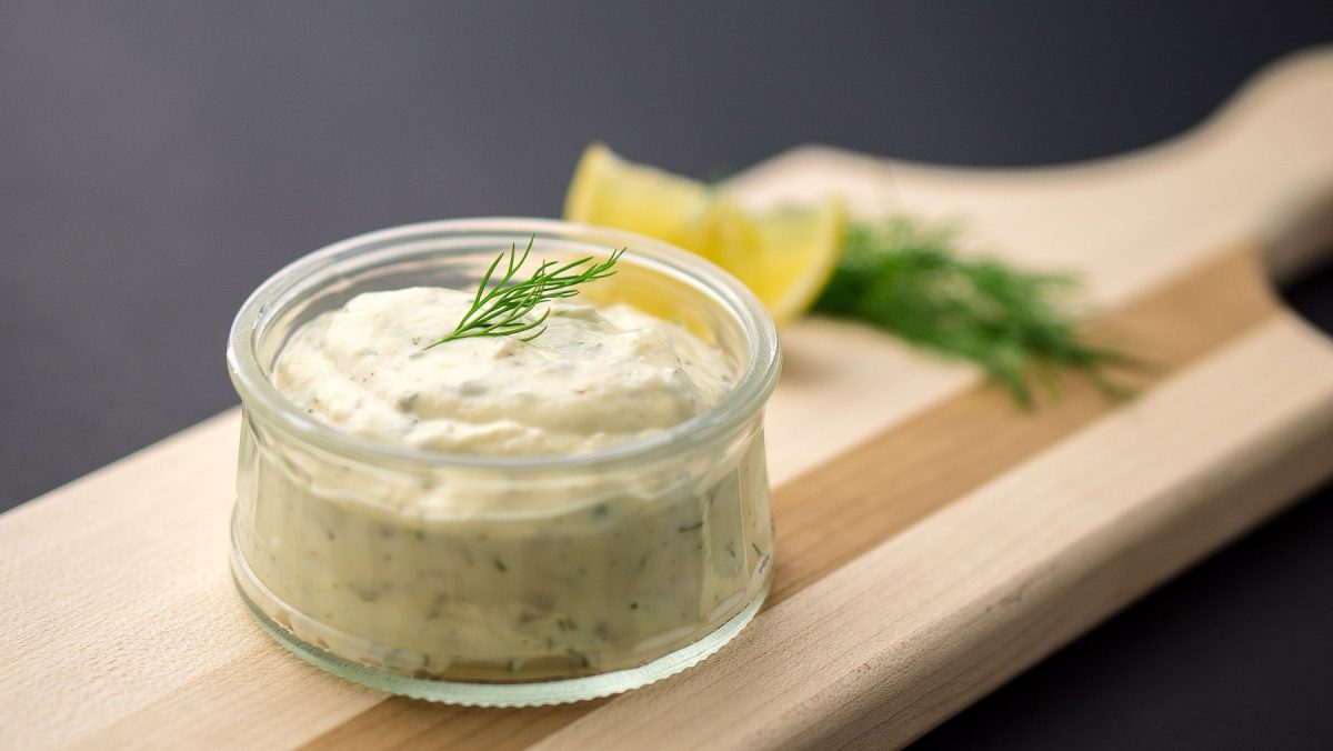 Dicke Krabbensauce aus Spargelwasser mit Dill und Zitrone, abgefüllt in ein kleines Dip-Glas auf einem Holzbrett serviert.