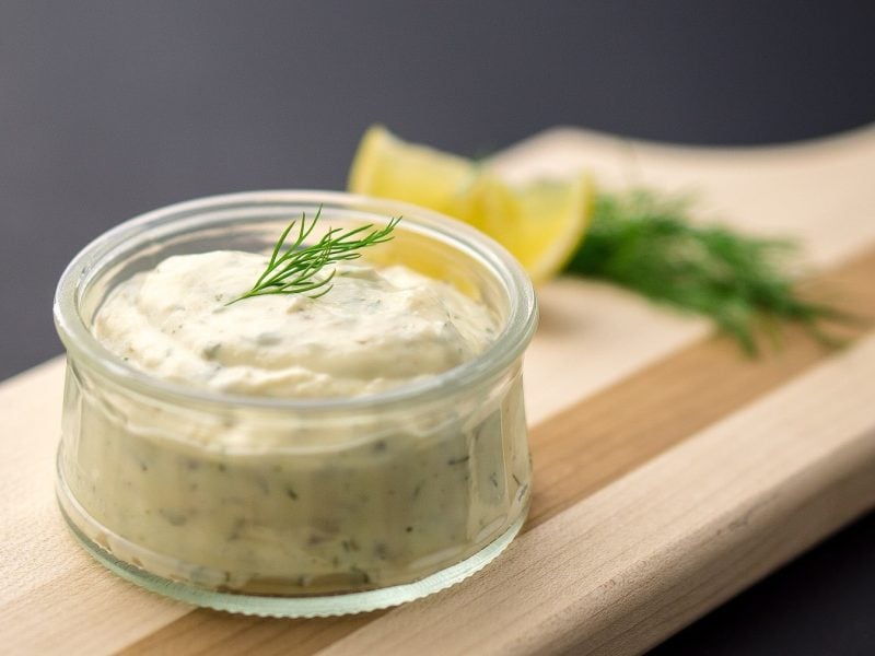 Dicke Krabbensauce aus Spargelwasser mit Dill und Zitrone, abgefüllt in ein kleines Dip-Glas auf einem Holzbrett serviert.