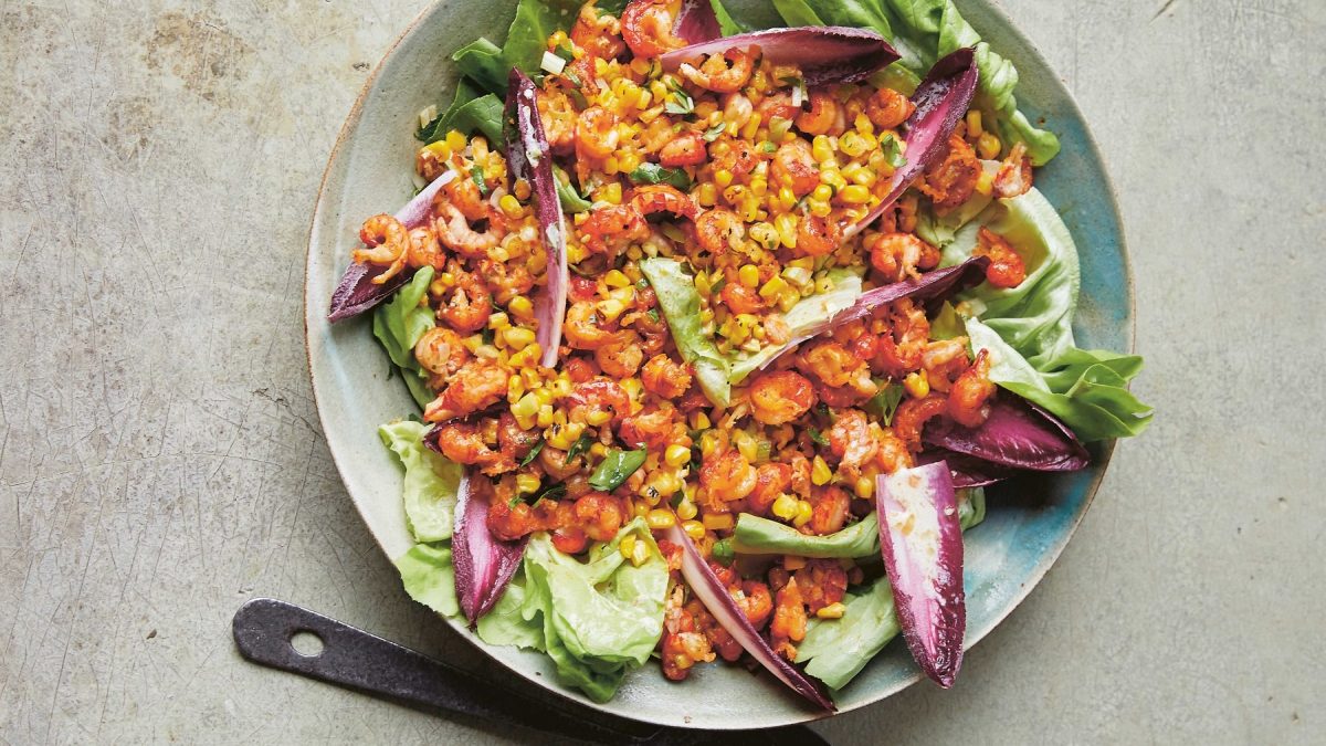 Ein Teller Krebs-Salat mit Mais und gemischtem Salat in der Draufsicht.