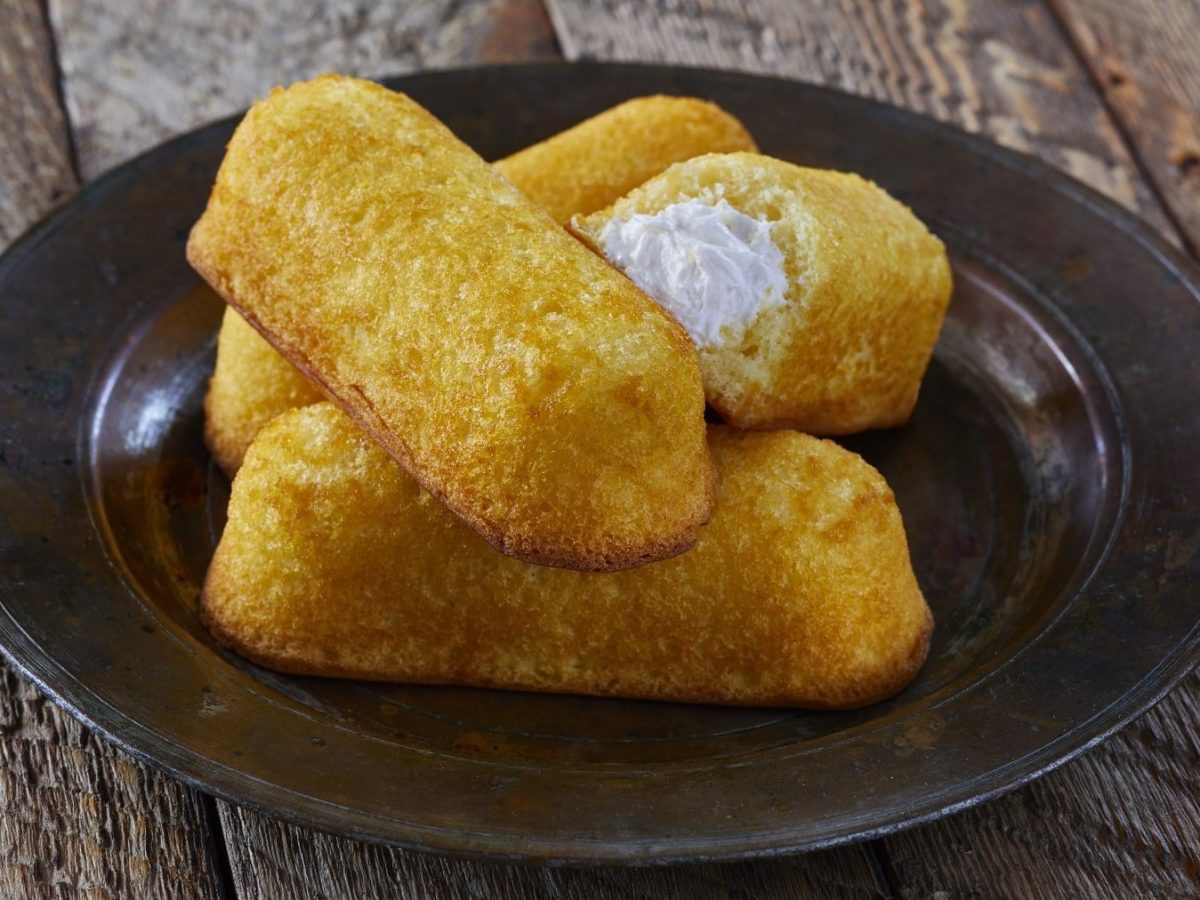 Twinkies selbst machen. Twinkies gefüllt mit einer Vanille-Sahne-Creme auf einem Teller auf hölzernem Untergrund.