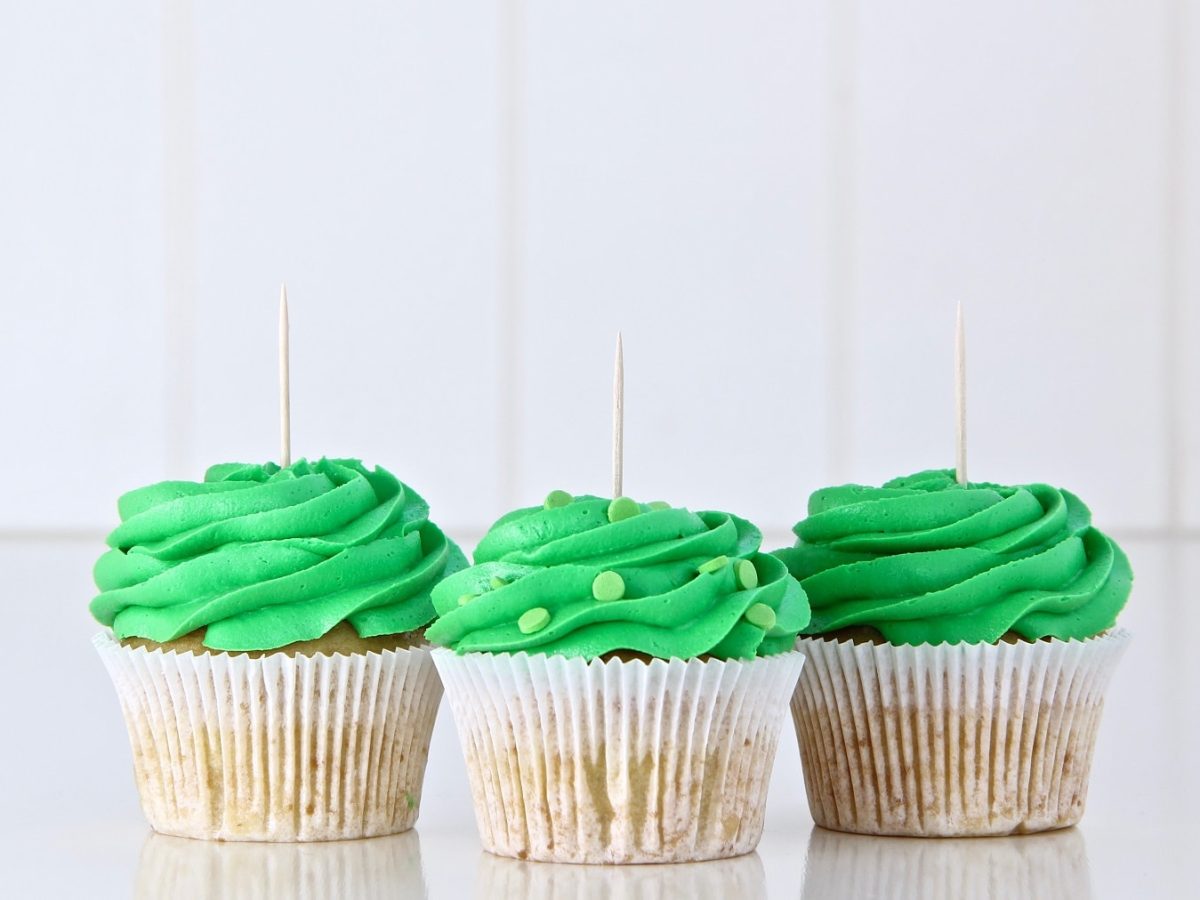 3 vegane Schoko-Muffins mit Minze vor weißen Fließen in hellem Setting.