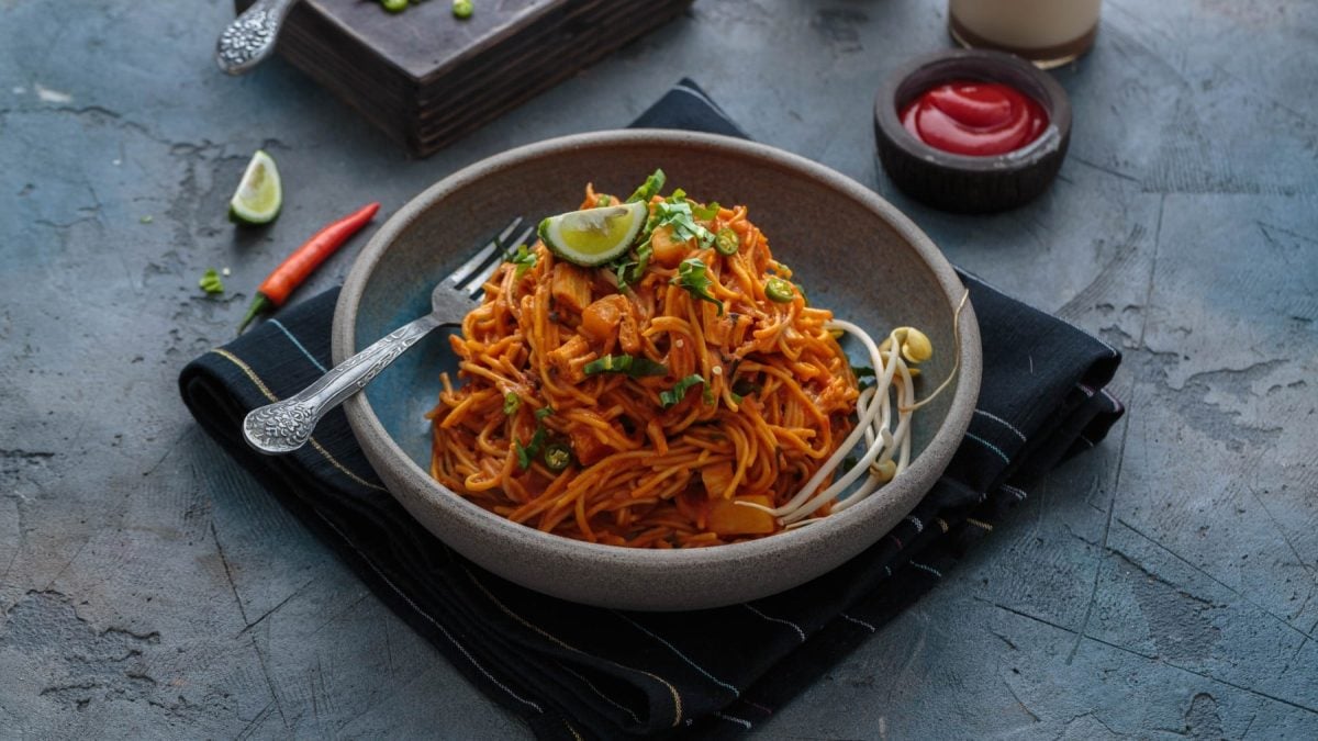 Mee Goreng Mamak in einer Schüssel auf einem Küchentuch. Im Hintergrund verschiedene Zutaten.