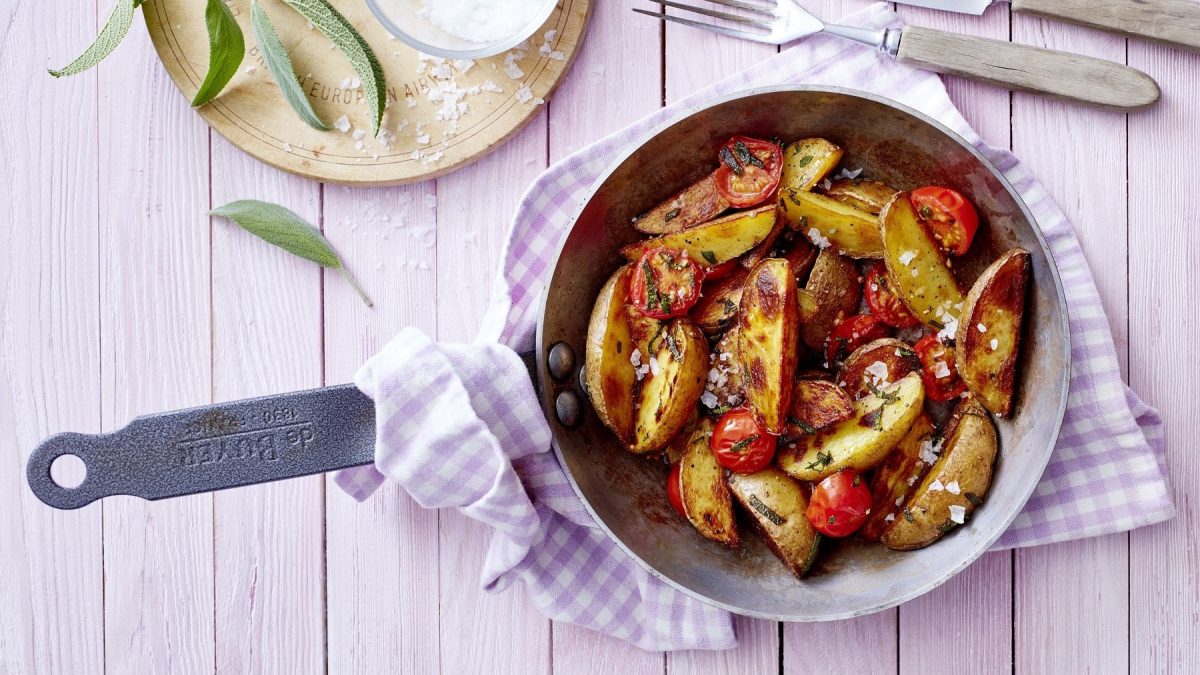 Mediterrane Kartoffeln in einer Pfanne auf einem lila Küchentuch auf einem Küchentuch