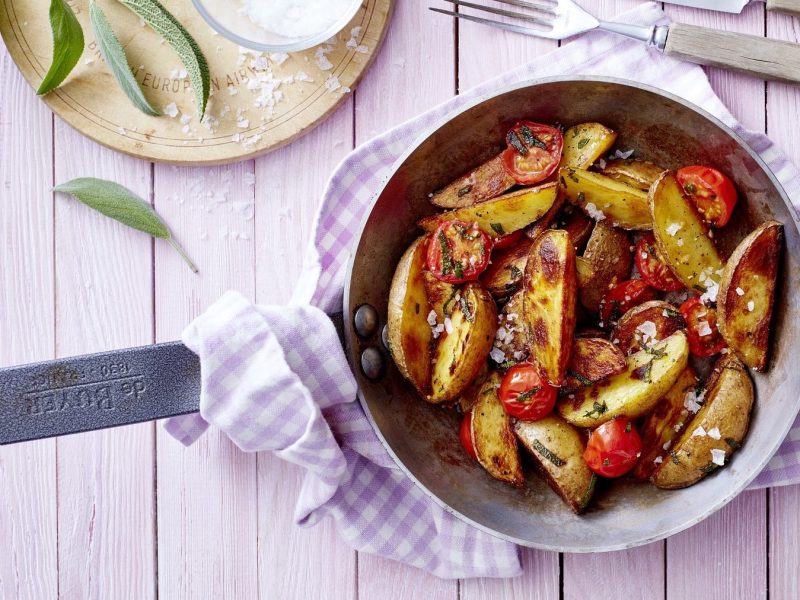 Mediterrane Kartoffeln in einer Pfanne auf einem lila Küchentuch auf einem Küchentuch