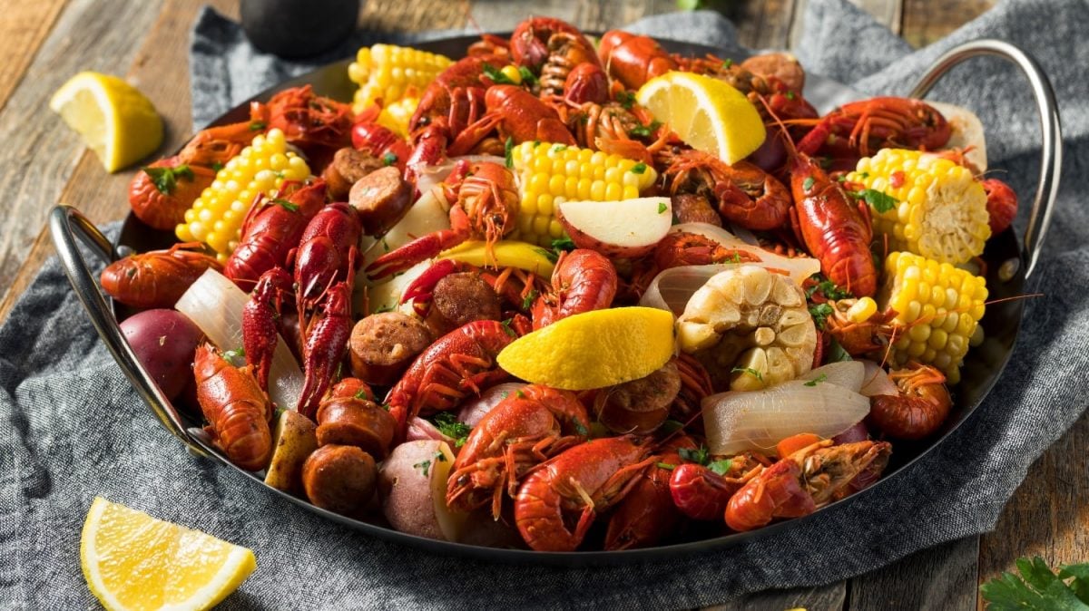 Eine gusseiserne Pfanne mit Seafood und Gemüse auf einem dunklen Holztisch.