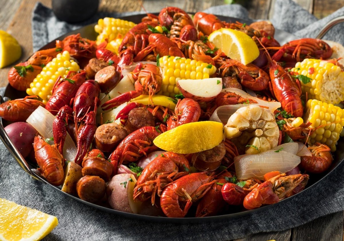 Eine gusseiserne Pfanne mit Seafood und Gemüse auf einem dunklen Holztisch.