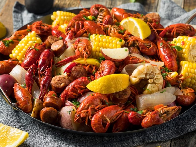 Eine gusseiserne Pfanne mit Seafood und Gemüse auf einem dunklen Holztisch.