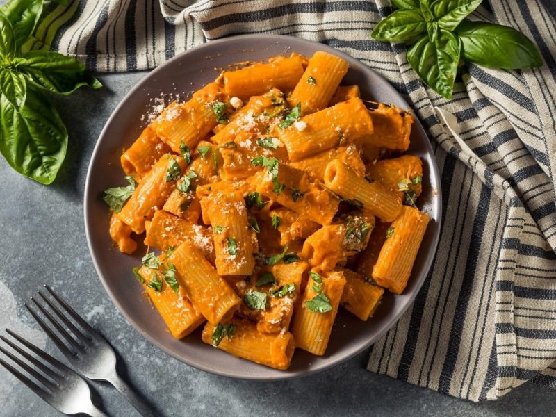 Eine Schüssel Gochujang Pasta neben Besteck und einem grau gestreiften Küchentuch