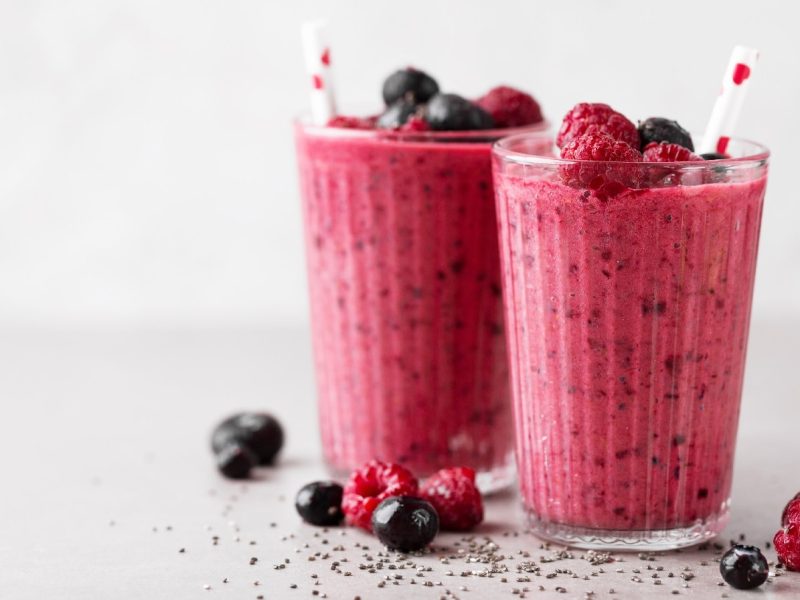 Kokos-Beeren-Shake mit Skyr in zwei Gläsern mit frischen Beeren