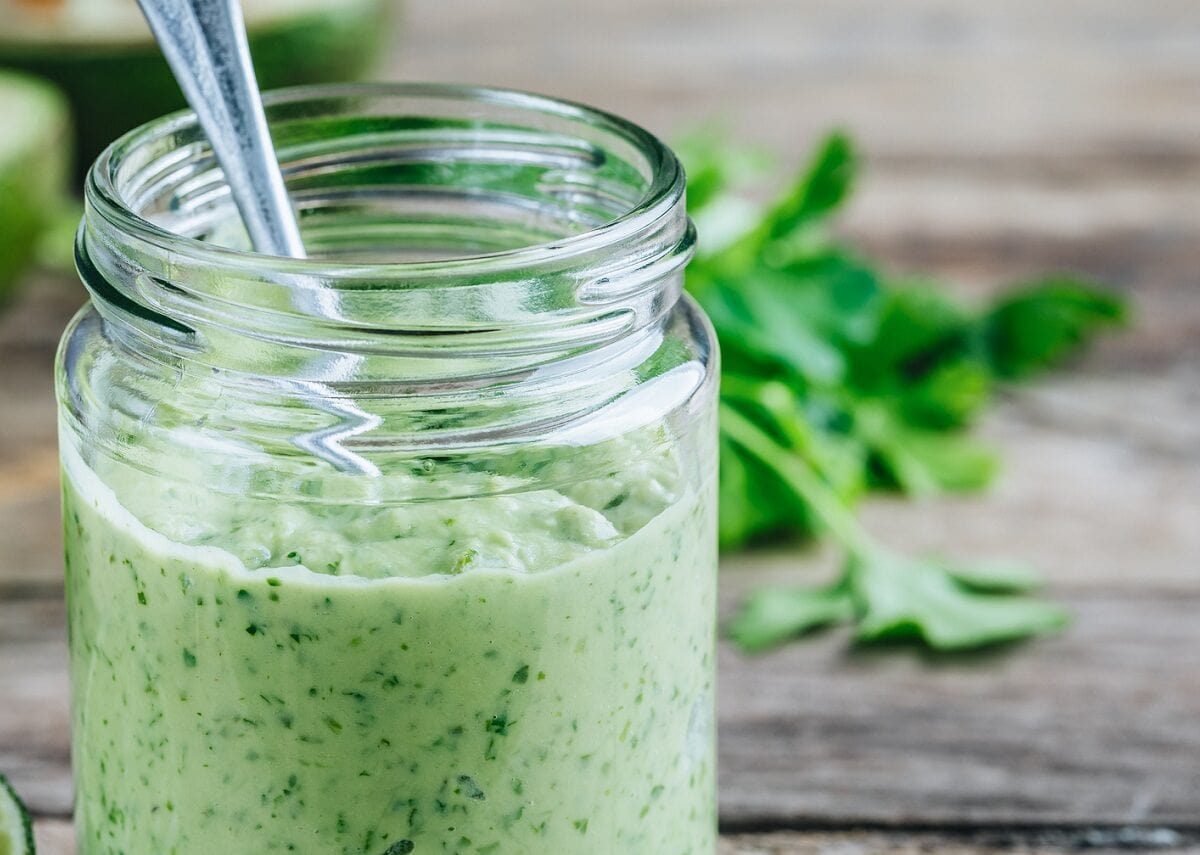 In einem Glas ist eine selbstgemachte Koriander-Mayonnaise mit Limetten.