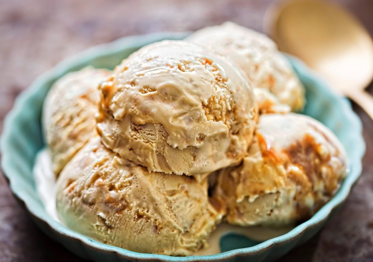 Fünf Kugeln Miso-Eis mit Karamell in einer hellblauen Schale auf dunklem Untergrund.