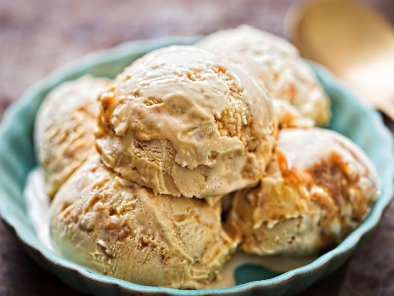 Fünf Kugeln Miso-Eis mit Karamell in einer hellblauen Schale auf dunklem Untergrund.