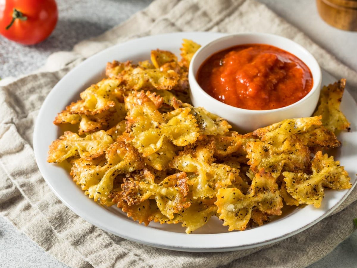 Pasta-Chips auf einem Teller. Daneben verschiedene Zutaten.