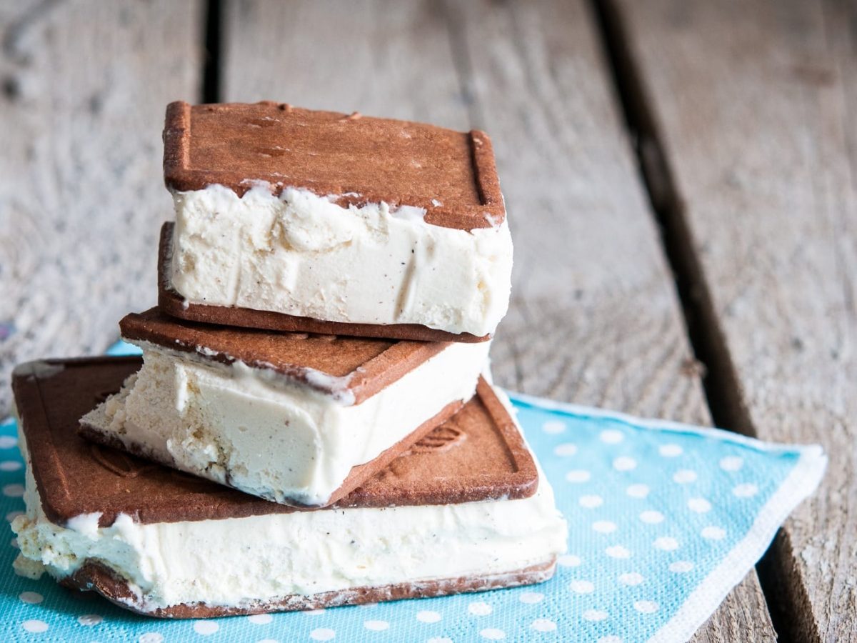 Drei vegane Milchschnitten gestapelt auf einer blauen Serviette auf rustikalem Holz.