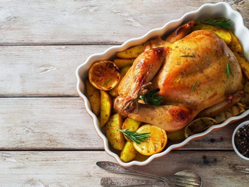 Eine weiße Auflaufform mit einem Zitronen-Huhn aus dem Backofen.